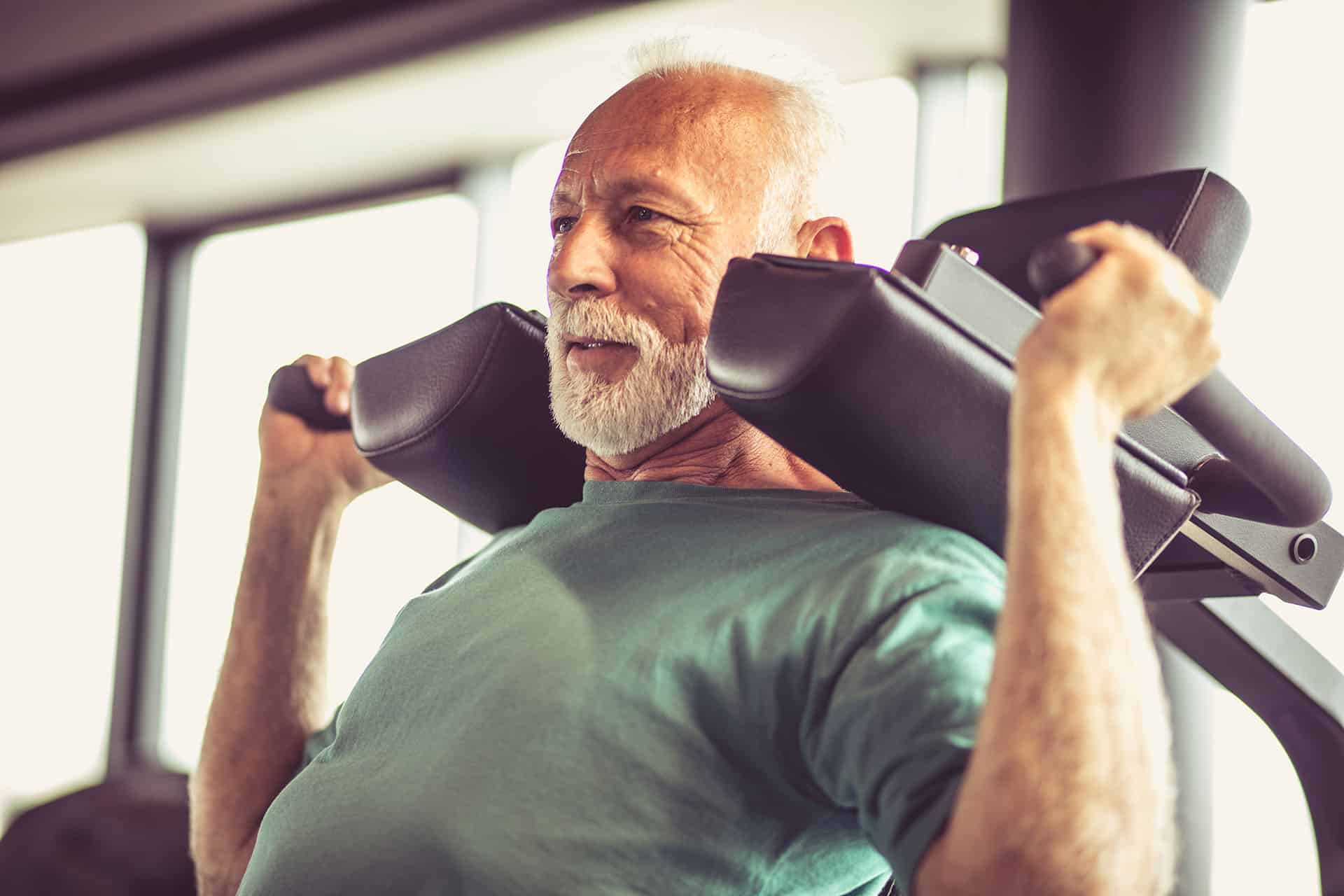 Älterer Mann beim Krafttraining im Fitnessstudio